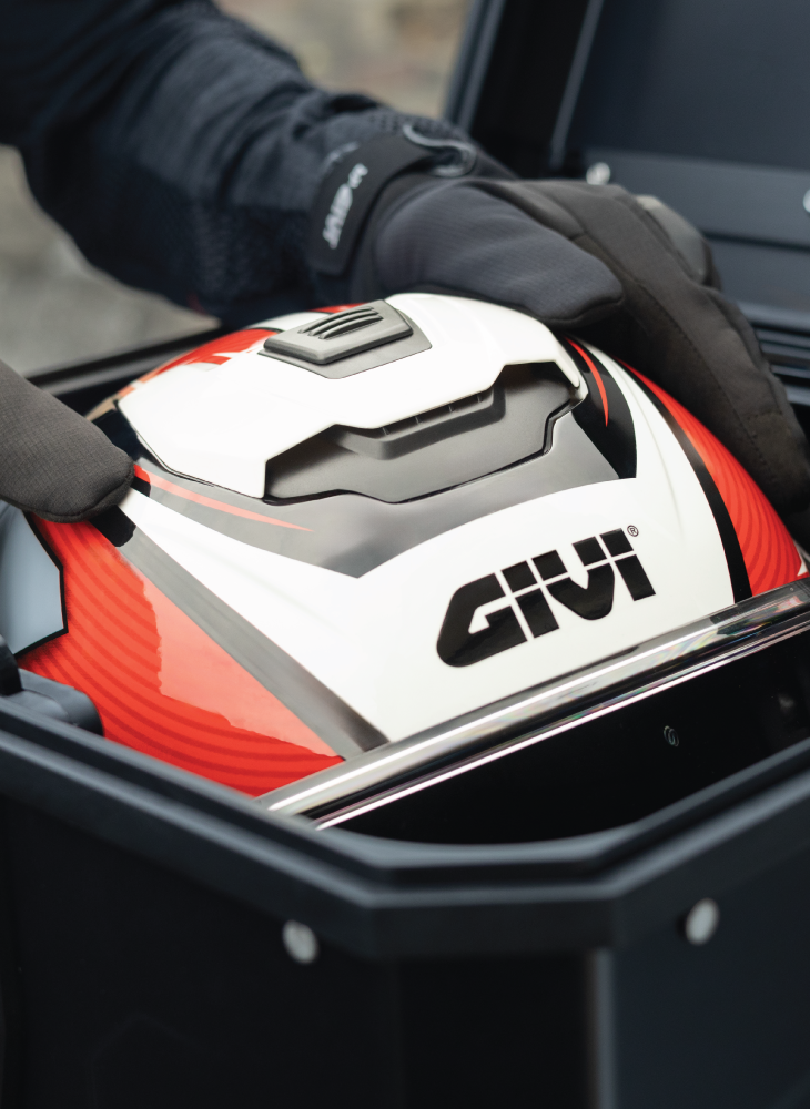 Close-up of a GIVI helmet being placed into a secure motorcycle storage case